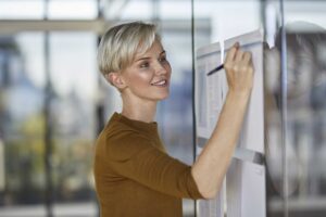 smiling-businesswoman-writing-on-papers-at-glass-p-2022-12-16-22-13-33-utc
